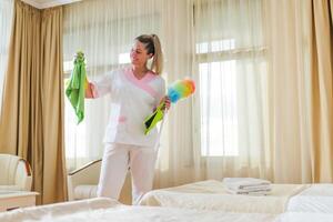 Beautiful hotel maid holding cleaning equipment. photo