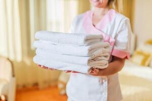 Close up image of hotel maid holding fresh and clean towels. photo