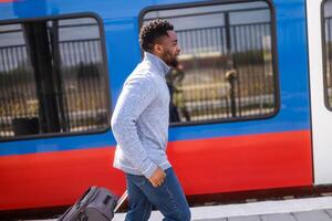 hombre corriendo a un dejando tren a lo largo ferrocarril estación con maleta. foto