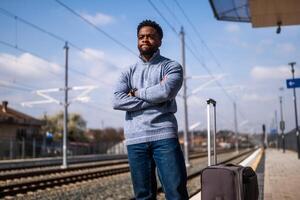 enojado hombre con un maleta en pie en un ferrocarril estación. foto