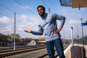 Angry man with a suitcase standing on a railway station. photo