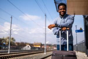 contento hombre con maleta en pie en ferrocarril estación foto
