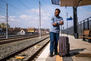 contento hombre con maleta en pie en ferrocarril estación. foto