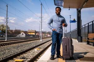 contento hombre con maleta en pie en ferrocarril estación. foto