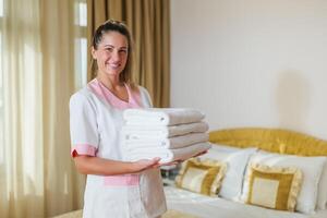 Portrait of beautiful hotel maid holding clean and fresh towels. photo