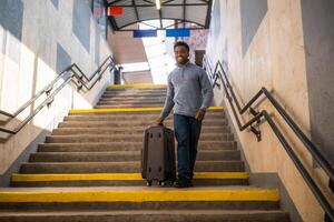 contento hombre con maleta caminando abajo un escalera en ferrocarril estación. foto