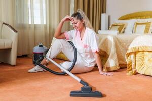 Image of sad overworked hotel maid sitting on the floor in a room. photo