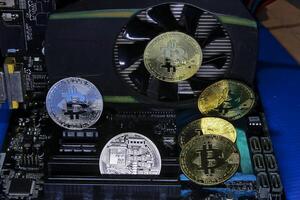 Gold and silver Bitcoin coins are placed on computer motherboards and on VGA graphics cards. photo