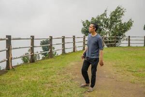 Young man stand on the grass field horse arena. The photo is suitable to use for calm enjoyed activity, leisure activity and park background.