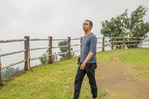 Young man stand on the grass field horse arena. The photo is suitable to use for calm enjoyed activity, leisure activity and park background.