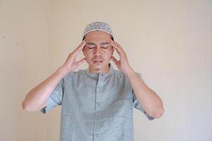 Moslem Asian man dizzy and headache face when Ramadan celebration. The photo is suitable to use for Ramadhan poster and Muslim content media.
