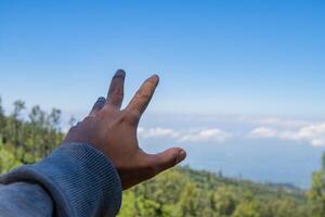 Man hand with sky background and mountain. The photo is suitable to use for adventure content media, nature poster and forest background.