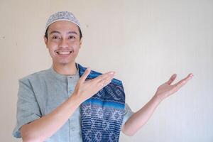 Moslem Asian man pointing the link gesture when Ramadan celebration. The photo is suitable to use for Ramadhan poster and Muslim content media.
