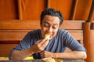 Man expression happy, smile, surprised when eat the banana fries. The photo is suitable to use for healthy care, man expression advertisement and daily activity content media.