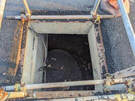 Man hole under ground trench with scaffolding hard barricade. The photo is suitable to use for industry background, construction poster and safety content media.