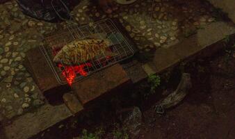 fish grilled over the charcoal fire when summer party. the photo is suitable to use for grilled content media and party poster.