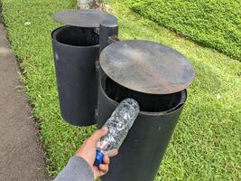 hombre lanzar botella en el basura compartimiento. el foto es adecuado a utilizar para ambiente y público parque contenido medios de comunicación.