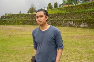 Young man stand on the grass field horse arena. The photo is suitable to use for calm enjoyed activity, leisure activity and park background.