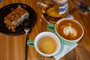 a cup of coffee and a cup of green tea and cake on a wooden table in a cafe. photo