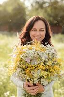 Portrait of a dark-haired girl with a large bouquet of wildflowers. photo