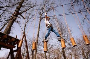 A boy in a helmet climbs a rope park in the spring photo