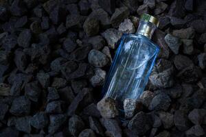 Perfume Blue transparent bottle in gravel or coral background photo