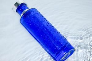 Perfume Dark Blue transparent bottle in water background photo