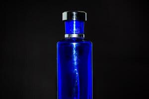 Transparent Dark Blue Bottle Perfume isolated black background for mock up design photo