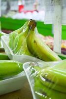 Banana in plastic wrap displayed in supermarket photo