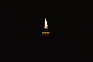 Single Candle with flame in the dark place, isolated black background photo