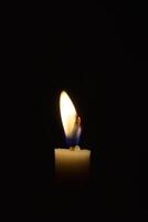 Single Candle with flame in the dark place, isolated black background photo