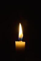 Single Candle with flame in the dark place, isolated black background photo