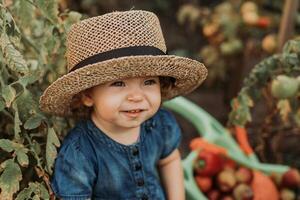 retrato de un linda pequeño niña en un azul vestir y un Paja sombrero en el otoño jardín. joven granjero foto