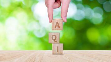 AQI, Abbreviation of air quality index word written on wooden blocks. text AQI on nature background, environment concept. photo