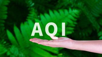 AQI, Abbreviation of air quality index, hand holding AQI on nature background, environment concept. photo