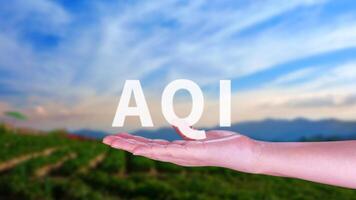 AQI, Abbreviation of air quality index, hand holding AQI on nature background, environment concept. photo