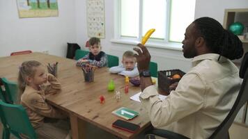 ett afrikansk amerikan lärare och en grupp av barn är studerar frukt och djur i de klassrum.skola för barn, undervisning tonåringar, få kunskap, lära sig de språk. video