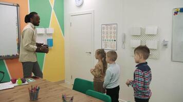 un africano americano profesor y un grupo de niños son estudiando frutas y animales en el aula.escuela para niños, enseñando adolescentes, ganancia conocimiento, aprender el idioma. video