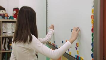 Kinder im schützend Masken lernen Englisch durch komponieren Wörter auf ein magnetisch Tafel während ein Pandemie. Schule zum Kinder, Lehren Jugendliche, dazugewinnen Wissen, lernen das Sprache. video