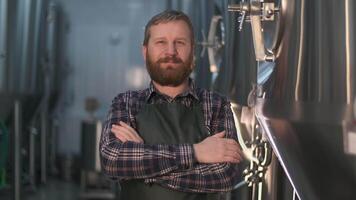 Portrait of a brutal brewer businessman with a beard in a beer factory. Camera movement forward video