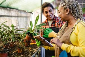 Happy multiracial women working together in plants and flowers garden shop photo