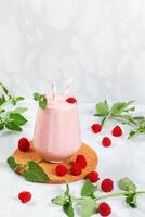Milkshake with raspberries in a glass glass with melissa leaves in the design with copy space photo