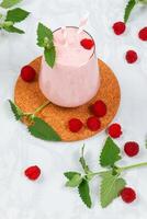 Milkshake with raspberries in a glass glass with melissa leaves in the design photo