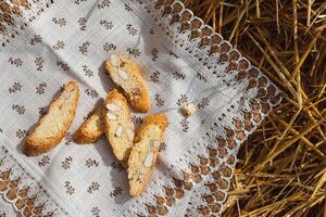 Almond cookies crackers with pieces of nuts lie on a napkin against a background of straw, top view photo