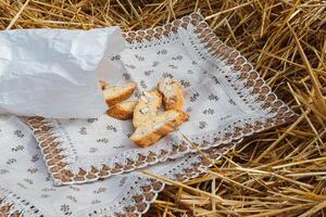 Almond cookies crackers with pieces of nuts fell out of a paper bag on a napkin lying on the straw photo