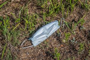 Discarded surgical mask polluting the environment photo