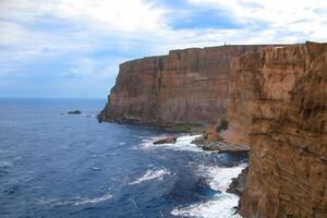 Seaside Majesty Breathtaking Coastal Cliffs Meet Stunning Blue Sea, A Spectacle of Nature's Grandeur photo