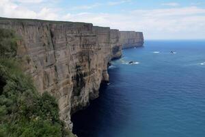 Seaside Majesty Breathtaking Coastal Cliffs Meet Stunning Blue Sea, A Spectacle of Nature's Grandeur photo