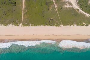 aéreo perspectiva capturas hermosa playa arena desde encima y alto, un tranquilo vista de costero felicidad foto