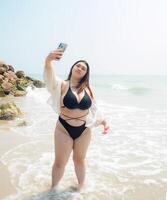 retrato joven asiático mujer grasa gordito linda hermosa sonrisa contento divertido disfrutar relajarse bikini trajes de baño cuerpo sexy frente ver mar playa blanco arena limpiar cielo azul calma naturaleza Oceano ola agua viaje en fiesta foto